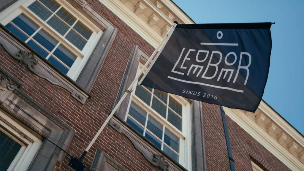 Golfers op de tee met clubhuis op achtergrond